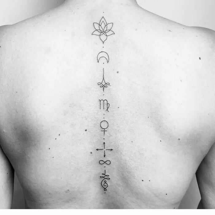 Minimalist spine tattoo with geometric symbols vertically aligned down the back.