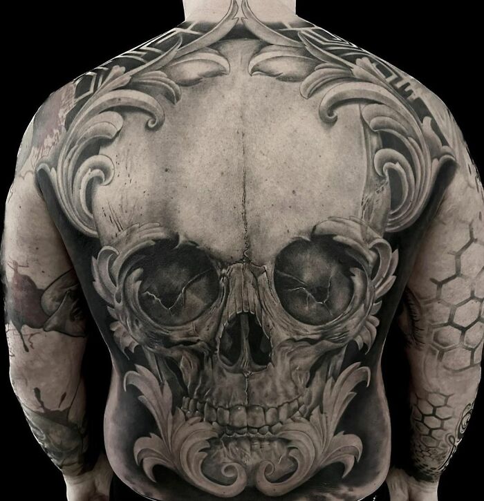 Realistic tattoo of an intricate skull design on a man's back, showcasing exceptional artistry.