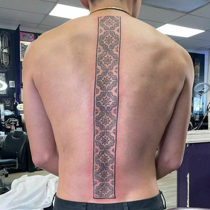 Detailed spine tattoo with elegant geometric design on a person's back.
