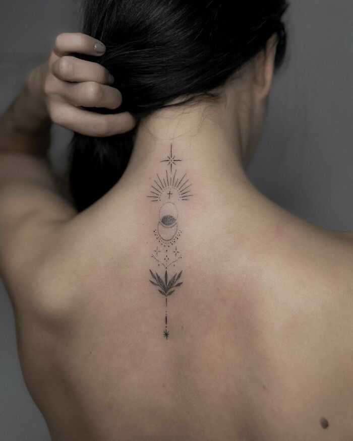Elegant spine tattoo featuring celestial and botanical designs on a woman's back.