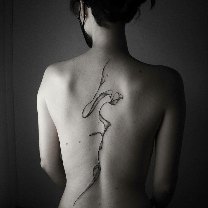 Intricate elegant spine tattoo design on a woman's back, showcasing fine abstract lines.