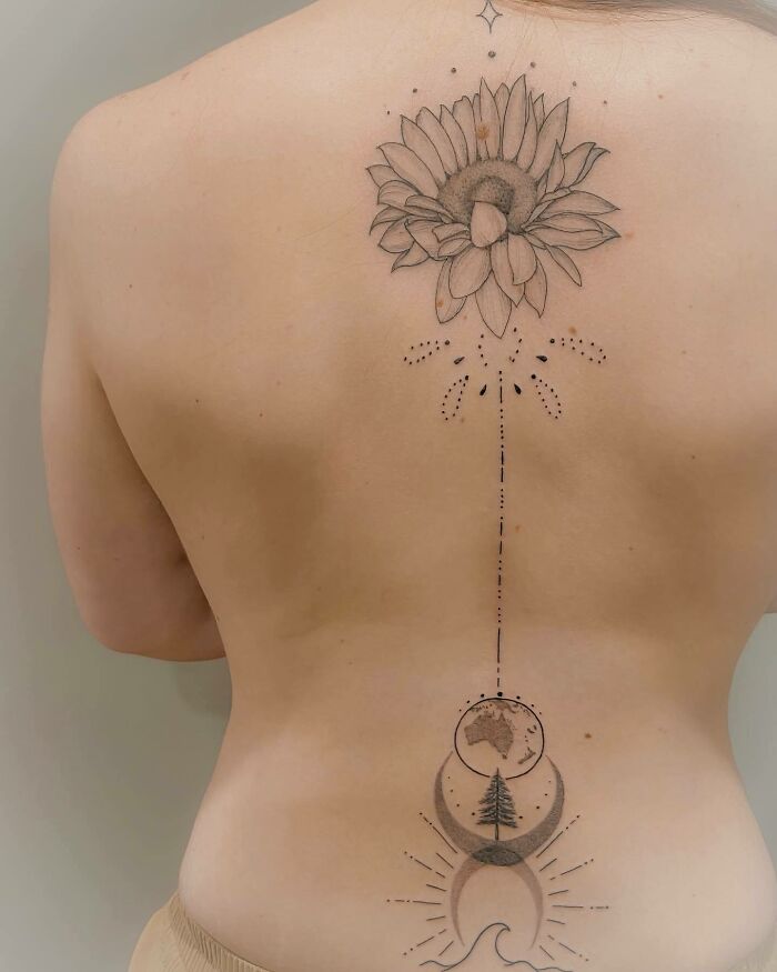 Elegant spine tattoo featuring floral and lunar designs along a woman's back.