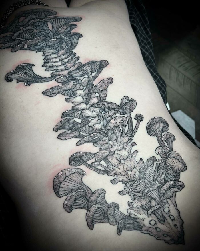 Elegant spine tattoo with intricate mushroom design on skin.