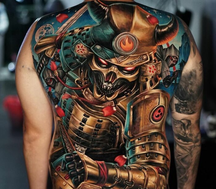 Realistic tattoo of a samurai warrior with intricate details, covering a person's back.