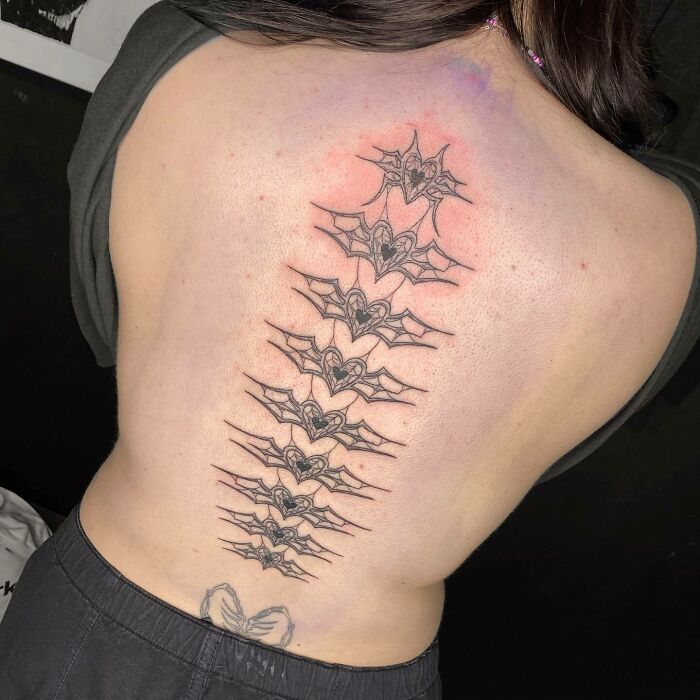 Elegant spine tattoo design featuring bat motifs down the back.