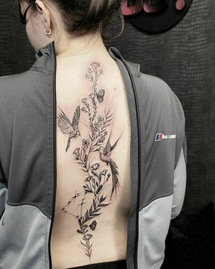 Beautiful spine tattoo featuring birds and flowers, showcasing intricate detail and artistry.
