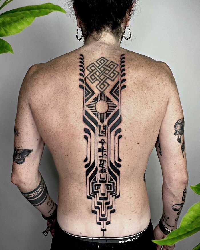 Elegant spine tattoo with geometric designs on a person's back.