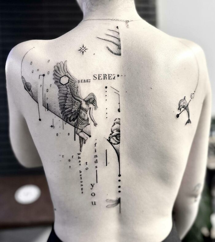Elegant spine tattoo with angelic design and abstract elements on a person's back.