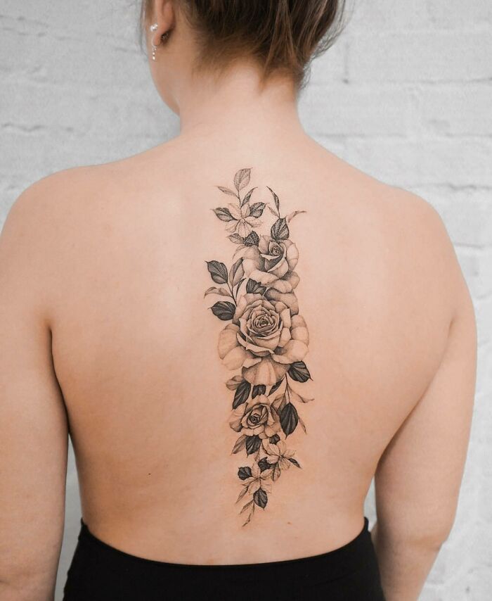 Elegant spine tattoo of floral design on a woman's back, showcasing intricate patterns and delicate artistry.