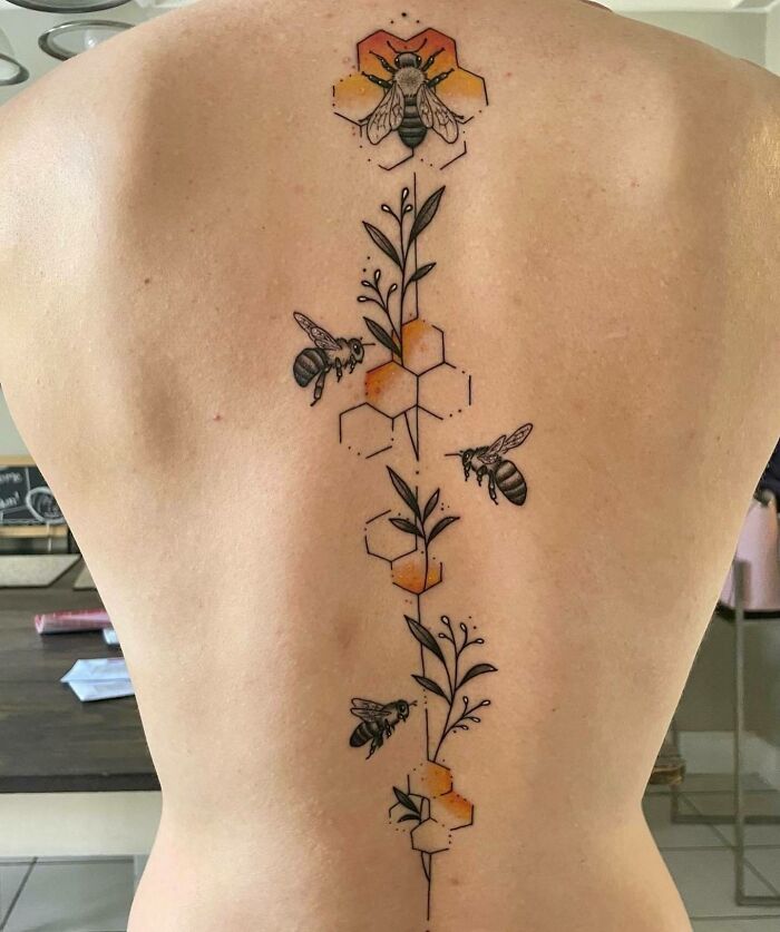 Spine tattoo with bees, floral elements, and hexagonal patterns, showcasing an elegant design for men and women.