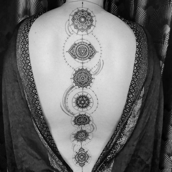 Intricate mandala spine tattoo design on a person's back, showcasing geometric patterns.