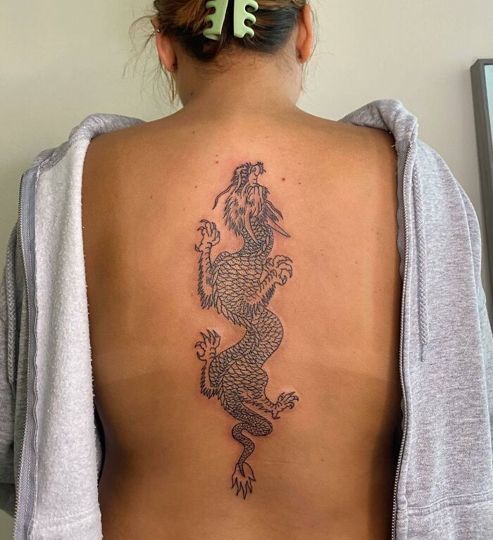 Elegant spine tattoo featuring a detailed dragon design on a person's back.