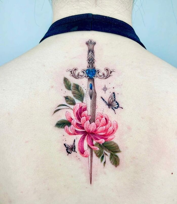 Beautiful spine tattoo featuring a sword with pink flowers and butterflies.