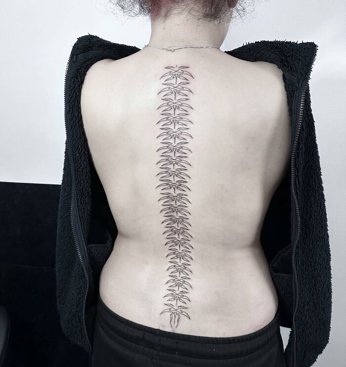 Elegant spine tattoo design with intricate patterns on a person's back, showcasing stylish ink art for men and women.