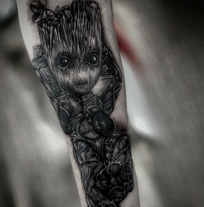 Marvel tattoo of Groot on forearm, detailed black and gray design.