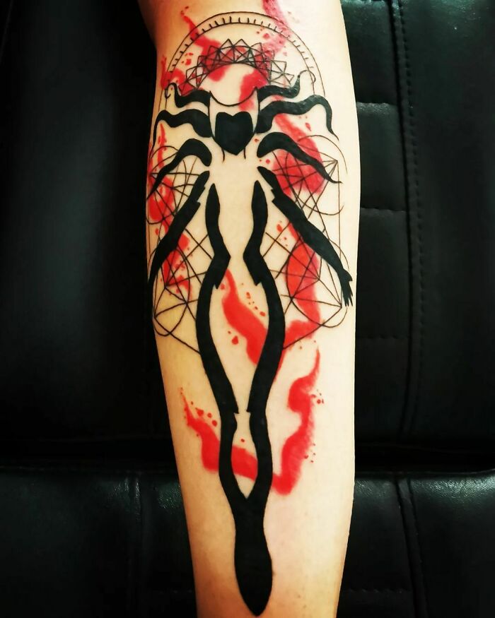 Marvel tattoo on arm featuring a black silhouette with red accents and geometric design.
