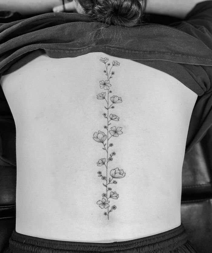 Elegant spine tattoo featuring a vertical floral design on a person's back.