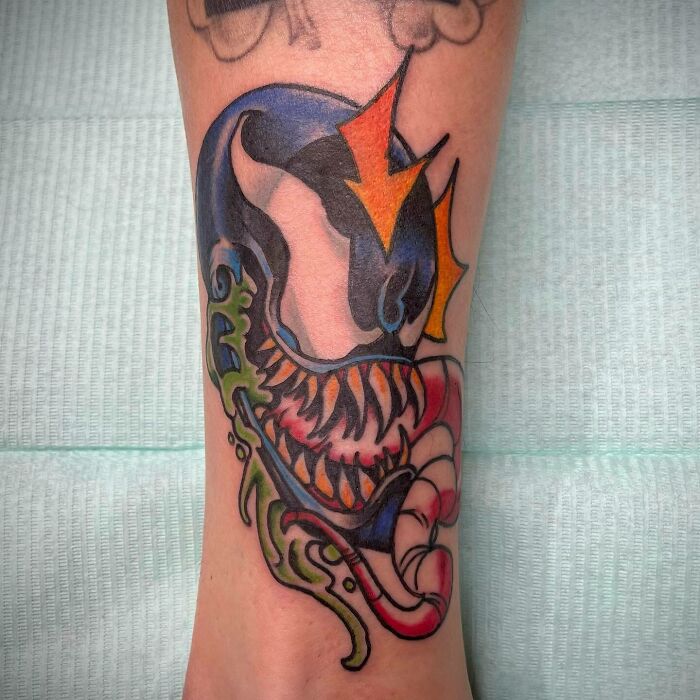 A colorful Marvel Venom tattoo with a bold, menacing design on a forearm.