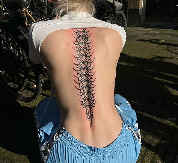 Person showing an elegant spine tattoo design outdoors.