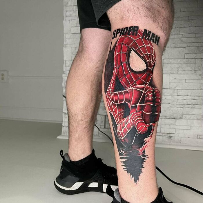 Spider-Man tattoo on a person's leg, showcasing Marvel superhero art in vibrant red and black colors.