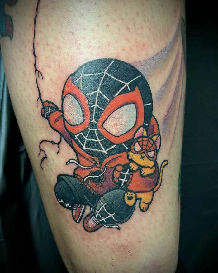 Cute Marvel tattoo of Spider-Man and a cat wearing matching costumes, showcasing colorful design elements.