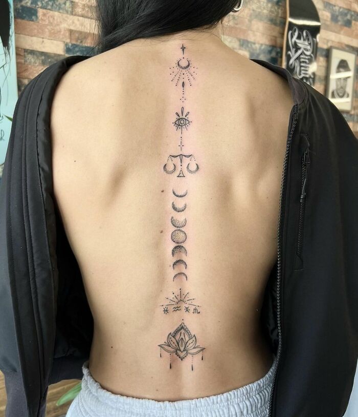 Elegant spine tattoo featuring moon phases and a lotus design.