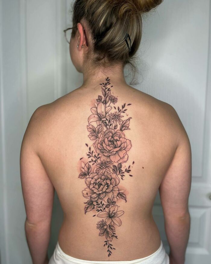 Person with an elegant floral spine tattoo, showcasing intricate design details.