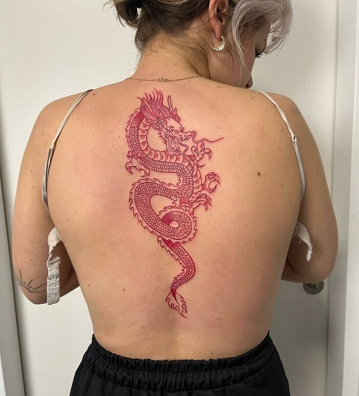 Woman with an elegant spine tattoo of a red dragon design.