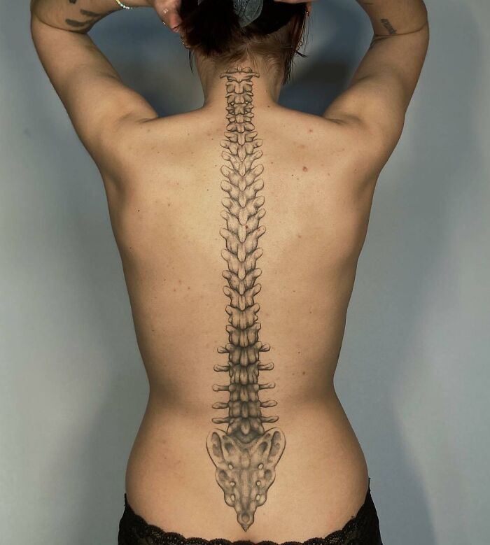 Elegant spine tattoo design on a person's back, featuring detailed vertebrae artwork.
