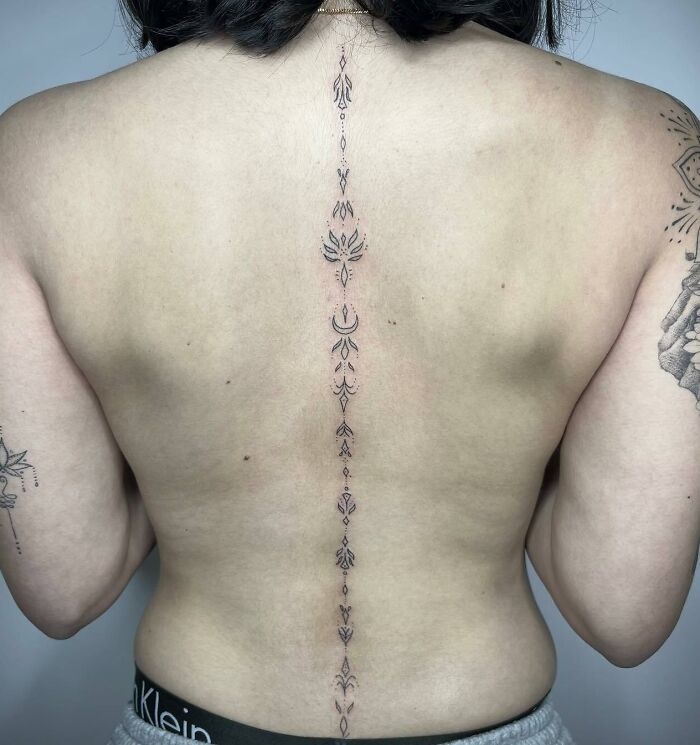 Elegant spine tattoo featuring intricate design on a person's back.