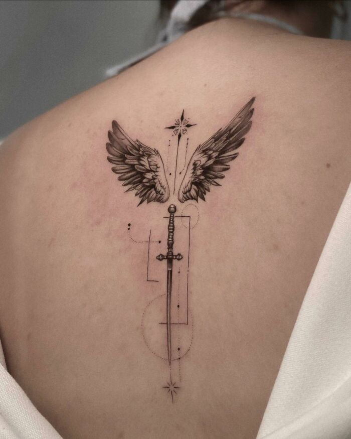 Elegant spine tattoo featuring a sword with wings and geometric accents on a person's back.