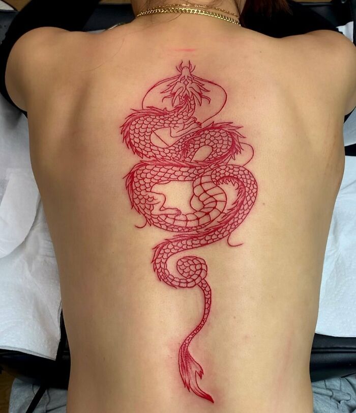 Elegant spine tattoo with a red dragon design on someone's back.