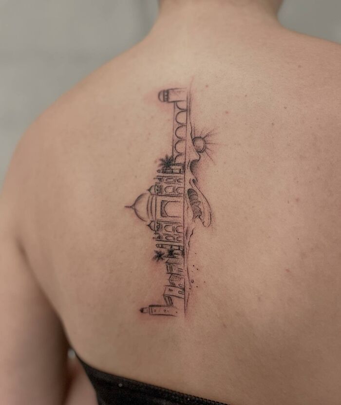 Elegant spine tattoo featuring a delicate architectural design on person's back.