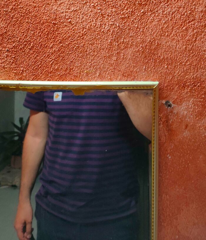 Tall man taking a picture of a small mirror 