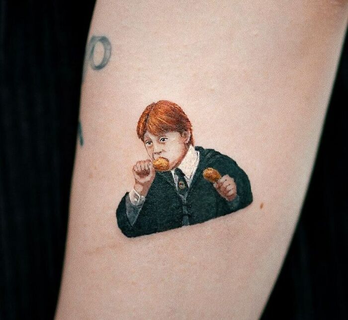 Harry Potter tattoo of a Ron Weasley eating, on a person's arm.