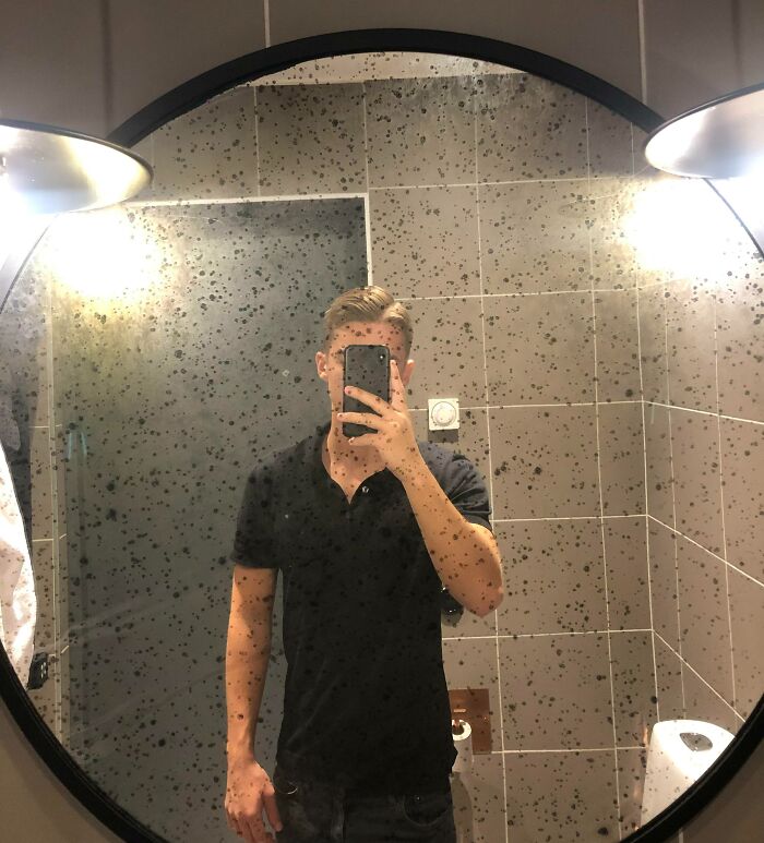 Spotted mirror reflection of a man taking a picture 