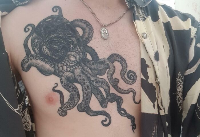 Space-themed tattoo of an octopus with galaxy details on a person's chest.