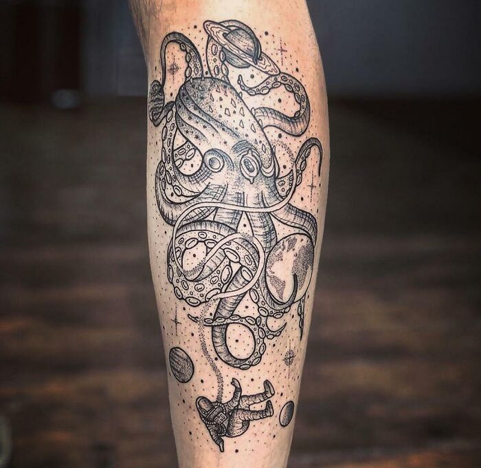 Space tattoo featuring an octopus with planets and an astronaut on a person's leg.