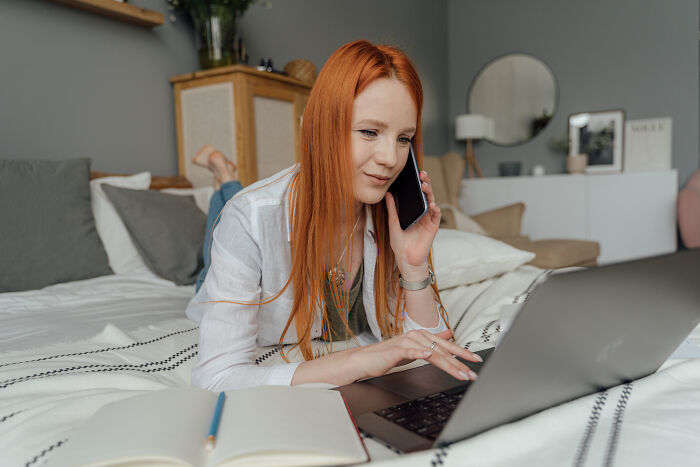 Woman talking on the phone and checking her laptop 