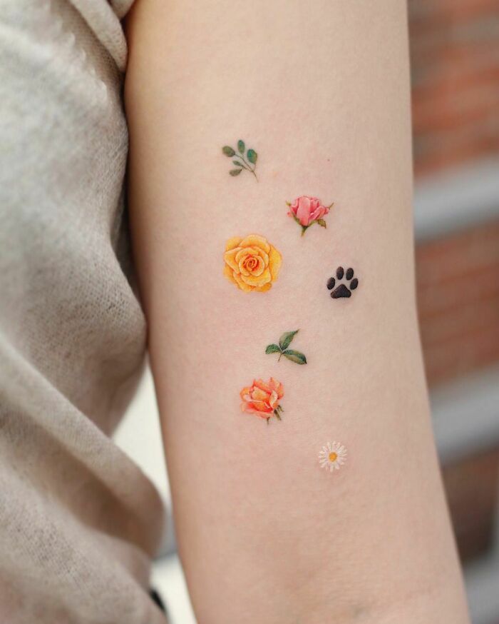 Color tattoos of flowers and a paw print on an arm, showcasing Saegeem's artistic style.