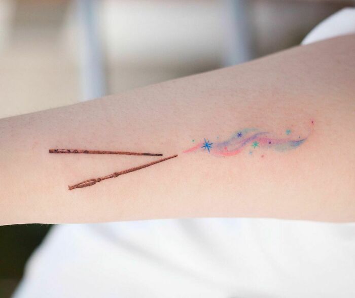 Color tattoo by Saegeem featuring magic wands and colorful starry design on forearm.