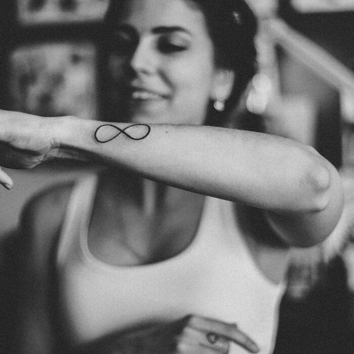 Woman showcasing an infinity wrist tattoo, timeless accessory idea.