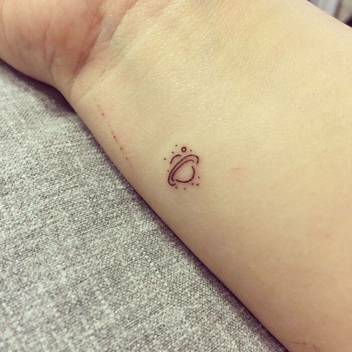 Small planet wrist tattoo design with orbit details in line art, showcasing unique tattoo ideas.