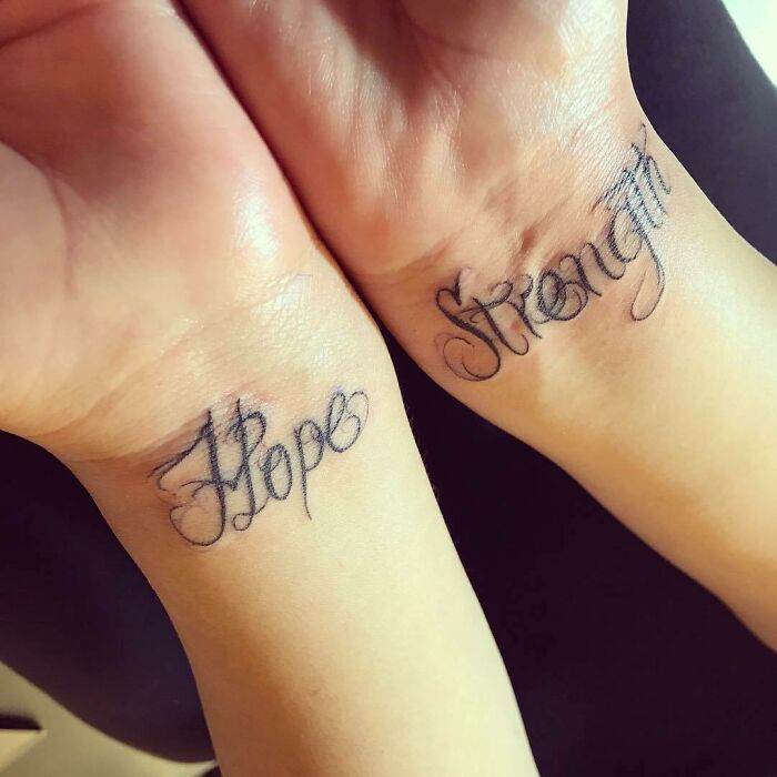 Wrist tattoo designs with the words “Hope” and “Strength” in cursive script on both wrists.