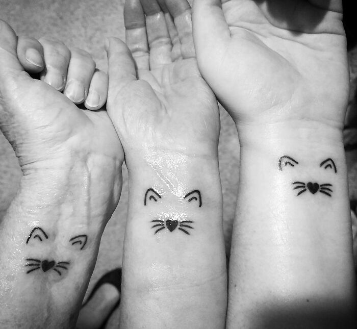 Three wrists featuring minimalist cat face tattoos, showcasing a stylish wrist accessory.