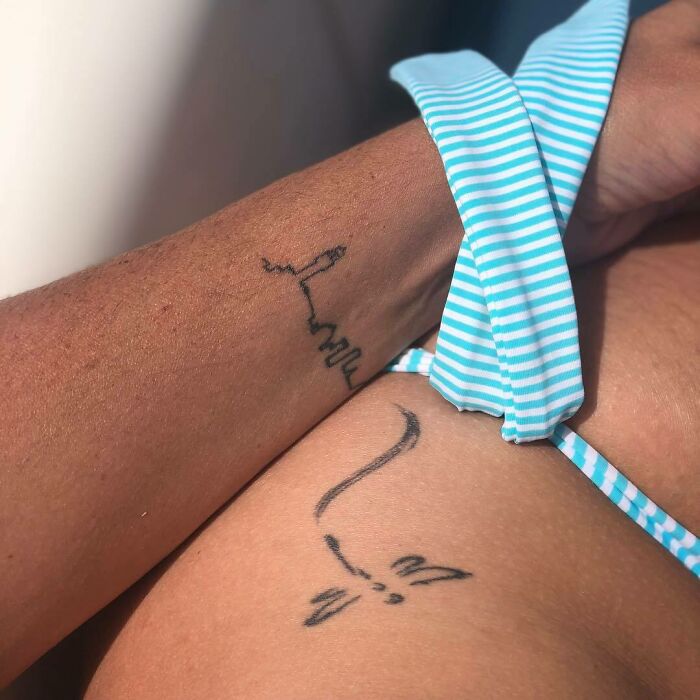 Stylish minimalist wrist tattoo with abstract line art, complemented by a striped fabric band as an accessory.