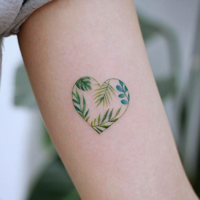 Heart-shaped color tattoo with leaf design by Saegeem on arm.
