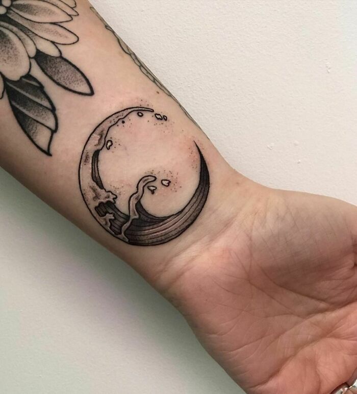 Wrist tattoo with a crescent moon and wave design, showcasing stylish tattoo ideas.