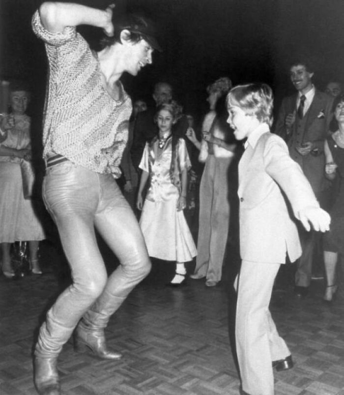Black and white historical photo of a man and boy dancing energetically with a crowd watching, capturing important historical moments.
