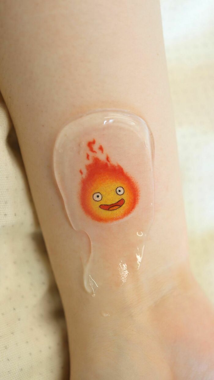 Color tattoo of a whimsical flame character on skin by Saegeem, resembling a playful art piece.